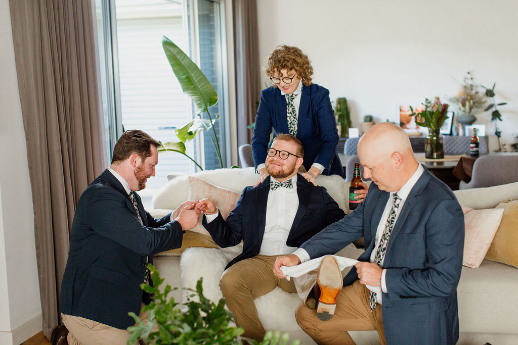 A groom is pretending to be pampered by his wedding crew as he gets ready for his wedding day
