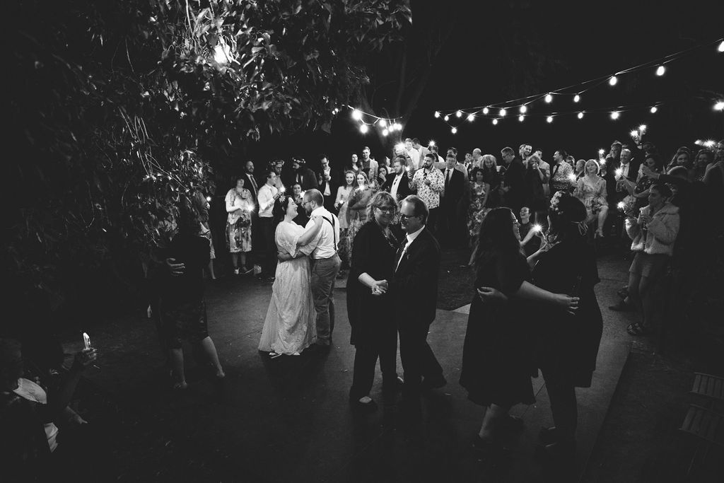 The bride and groom dance under the fairy lights and stars to their first dance as their family join them on the dance floor