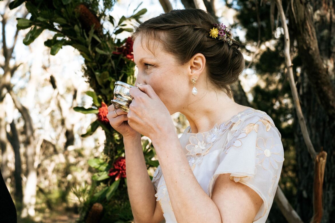 A bride wearing a vintage wedding dress drinks from a Scottish quaich in her wedding ceremony