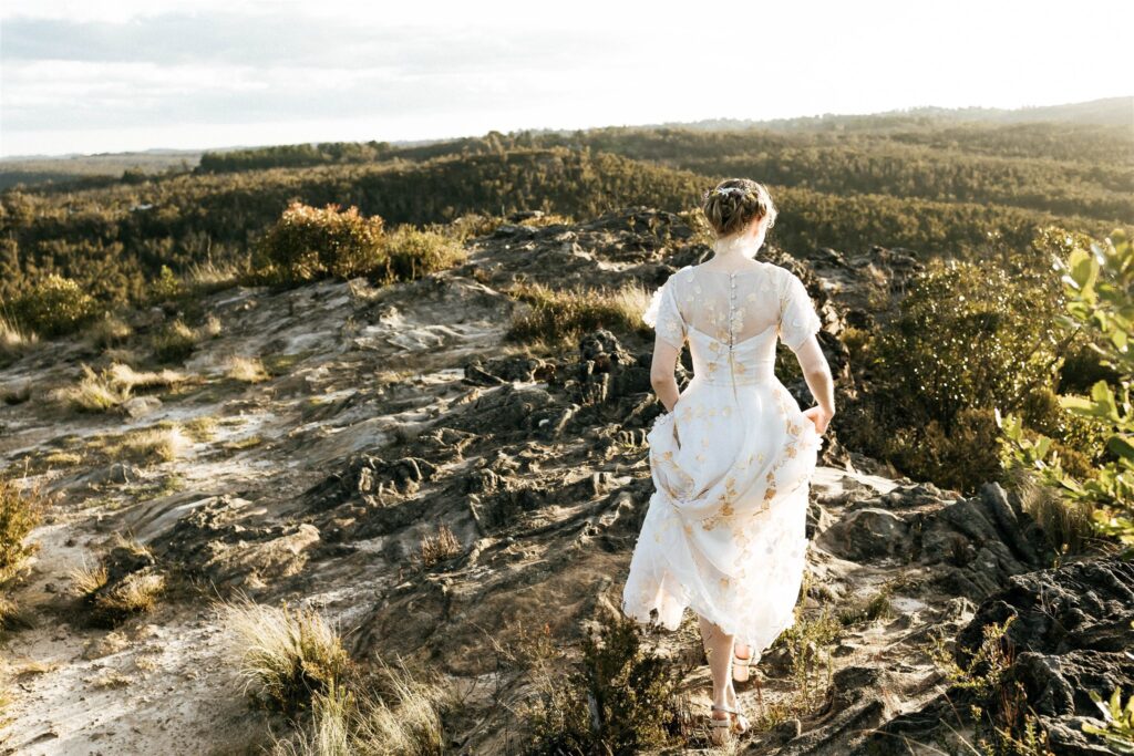 A bride wearing a vintage wedding dress walks over the rocks in the Blue Mountains