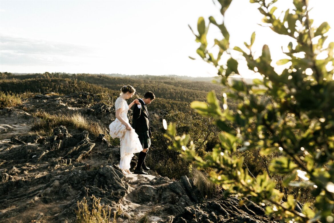 A bride wearing a vintage wedding dress and a groom wearing a kilt, walk arm in arm in the Blue Mountains