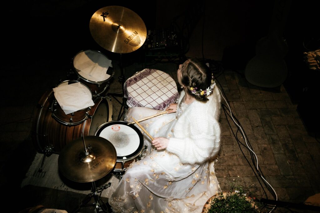 A bride wearing a wedding dress, plays the drum at her wedding