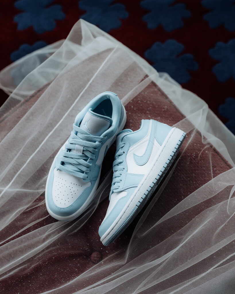 A pair of light blue and white Nike sneakers are placed on top of a wedding veil