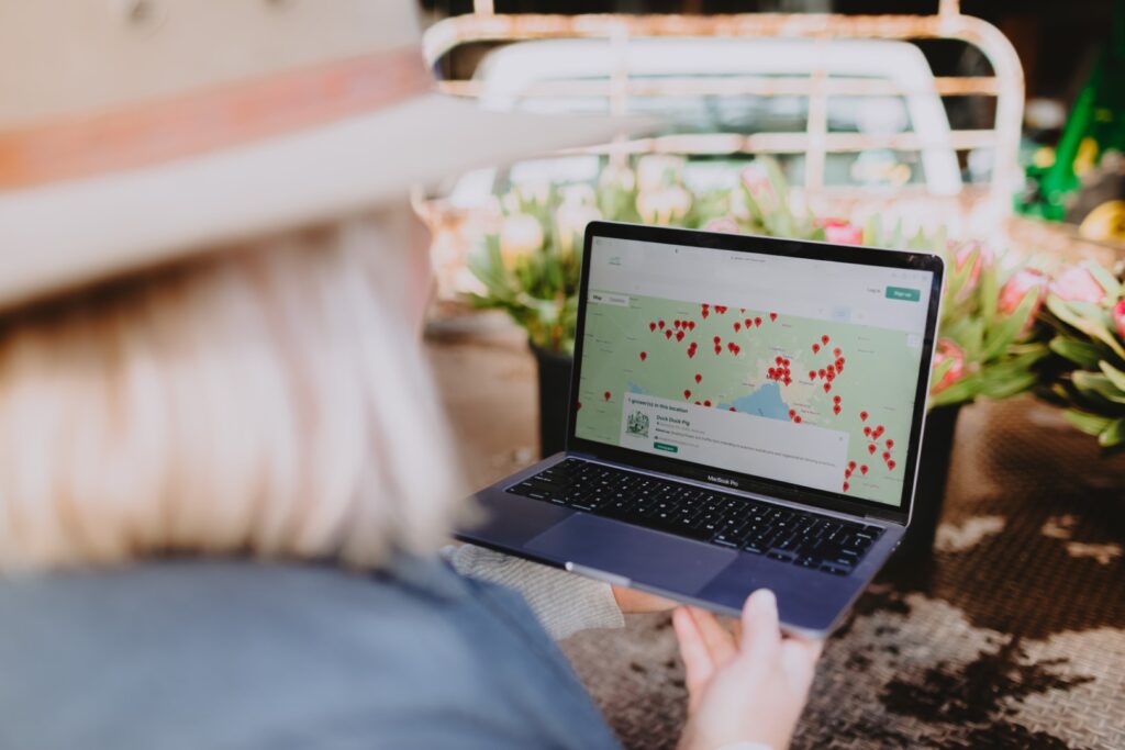 Nikki Davey from Grown Not Flown is using a laptop on the Grown Not Flown website to locate locally grown flowers in Australia