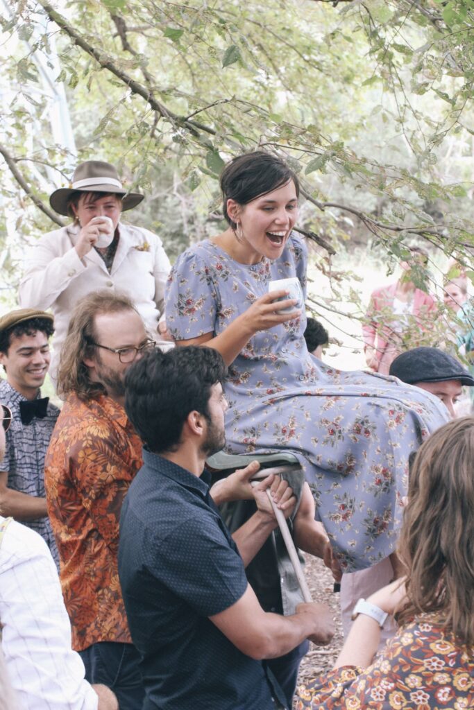 A wedding in a community garden in Fitzroy where all the guests are carrying the brides in chairs through the crowd